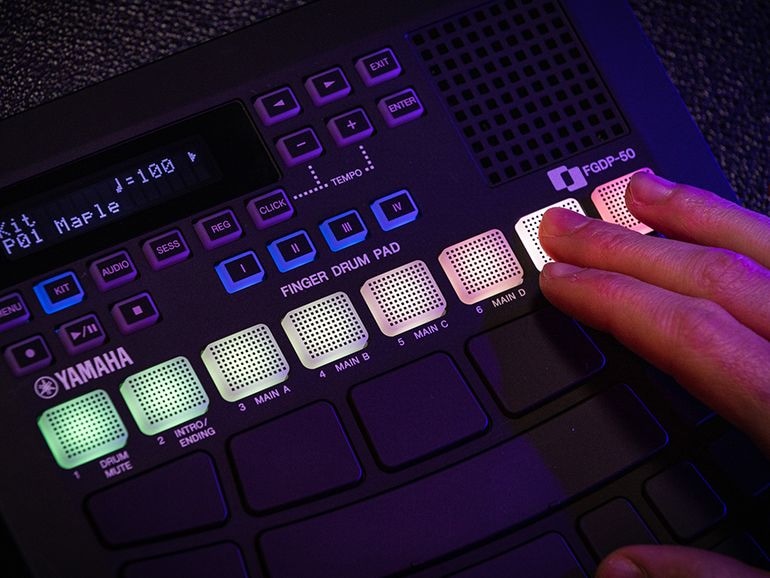 Close-up of fingers touching the glowing RGB pads on the FGDP-50